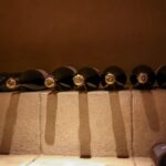 Botellas de vino tumbadas en un botellero de madera en un rincón fresco y en penumbra