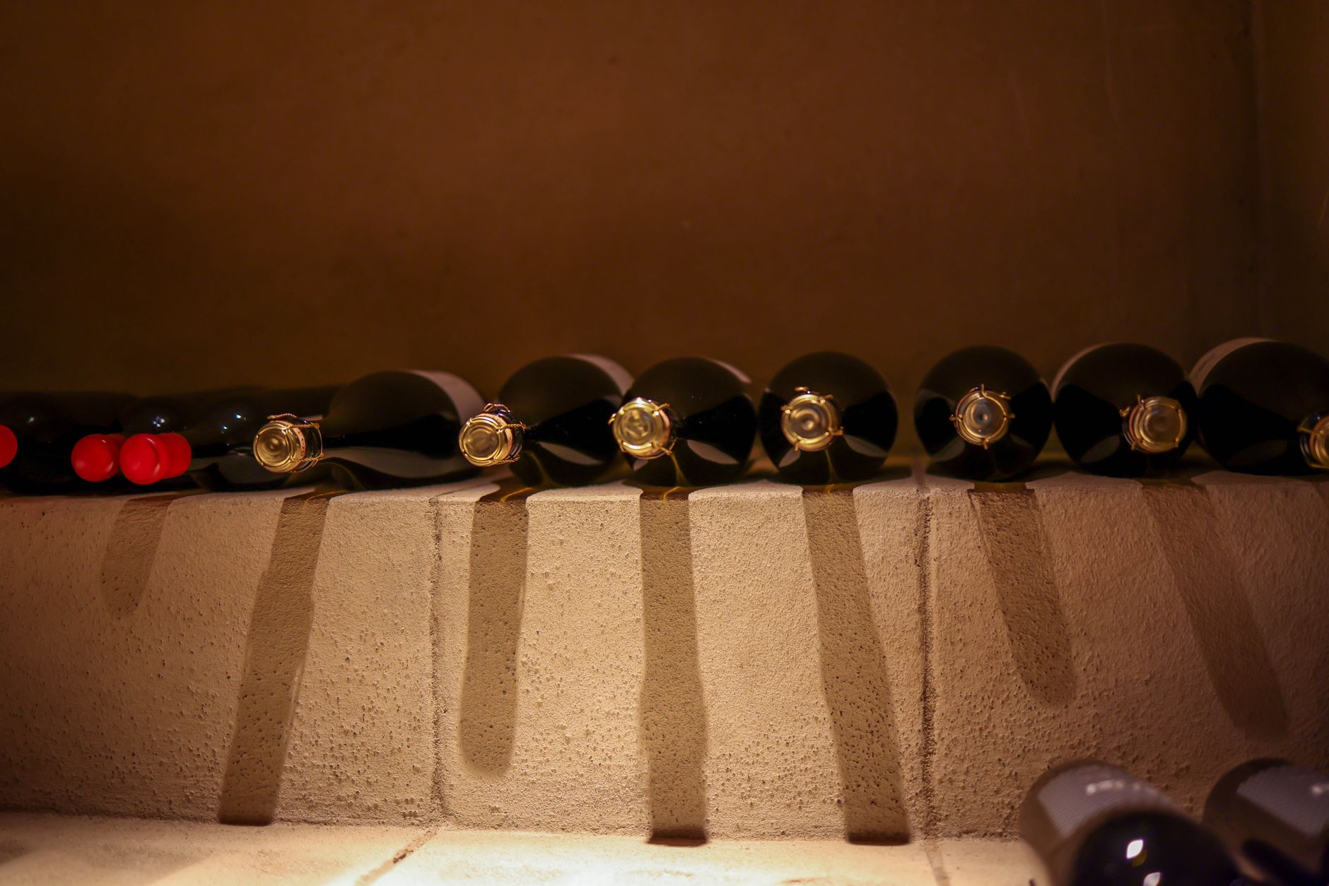 Botellas de vino tumbadas en un botellero de madera en un rincón fresco y en penumbra