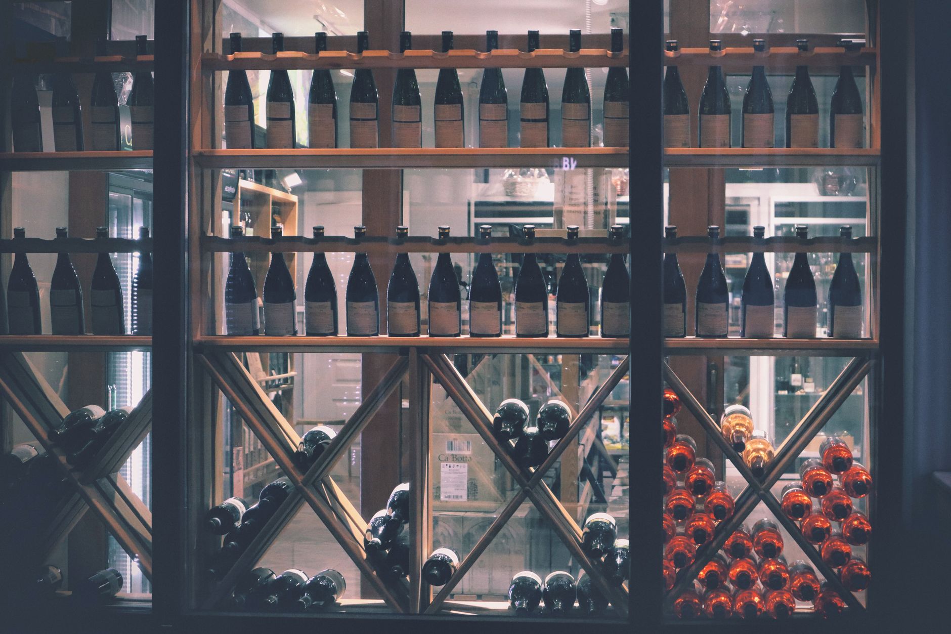 Persona revisando varias botellas de vino junto a un portátil antes de comprar