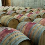 Hilera de barricas de roble en una bodega subterránea donde envejece el vino