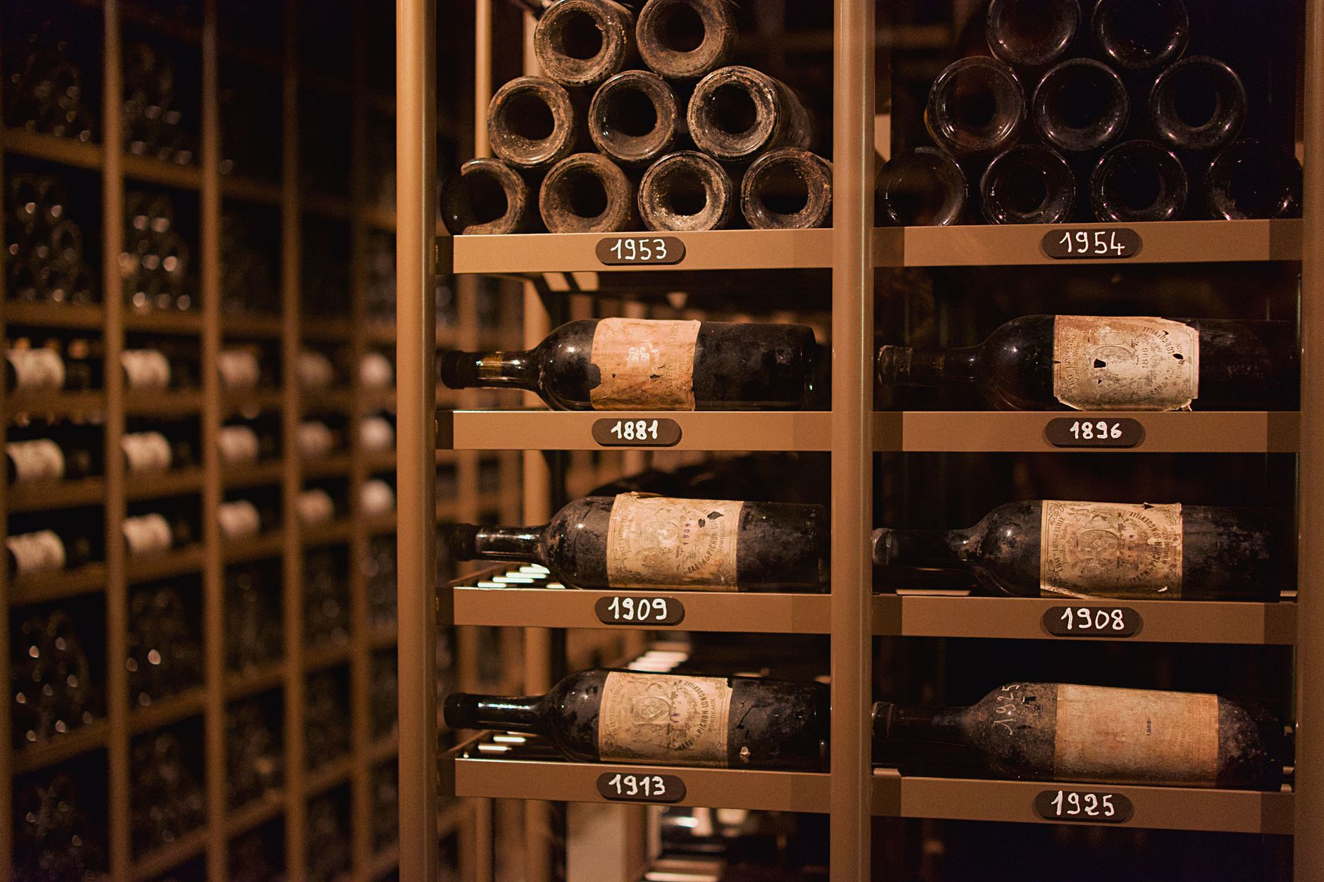 Botellas de vino con etiqueta en una bodega de guarda, con la añada visible en una de ellas