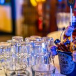 Botella de vino blanco enfriándose en una cubitera junto a dos copas sobre una mesa