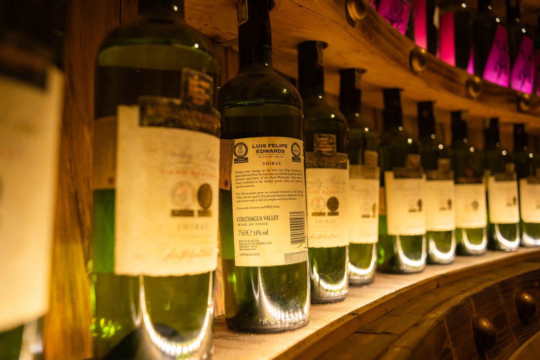 Copa de vino y botellas en una bodega, con la etiqueta a la vista
